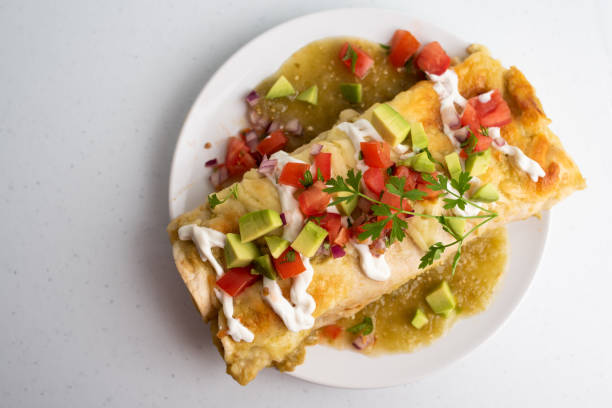 Honey lime chicken enchiladas with toppings Honey lime chicken enchiladas with toppings of avocado and tomato, marinated in green Verde sauce enchilada stock pictures, royalty-free photos & images