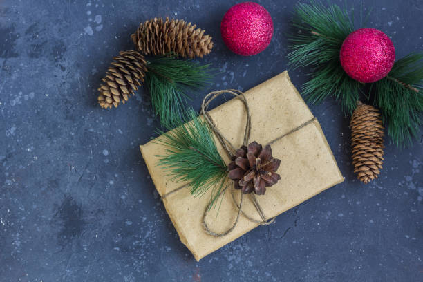 istock Christmas composition. Gift wrapping in kraft paper, fir tree branches, pine cones, red decorations on a dark background. Christmas, winter holidays, new year concept. 1272729280