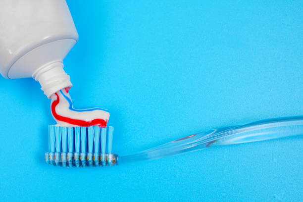 istock putting toothpaste on toothbrush on blue background with copy space 1272730956
