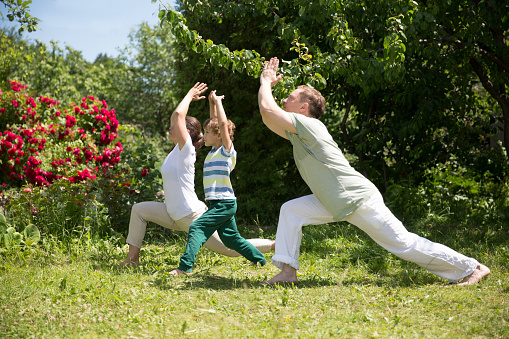 Family father, mother and  son preschool child practice Tai Chi Chuan in a park.  Chinese management skill Qi's energy. solo outdoor activities. Social Distancing