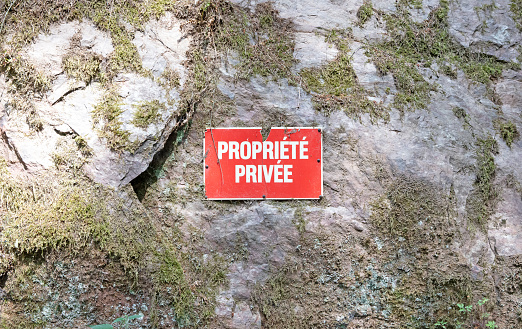 No trespassing private property red sign on a stone wall