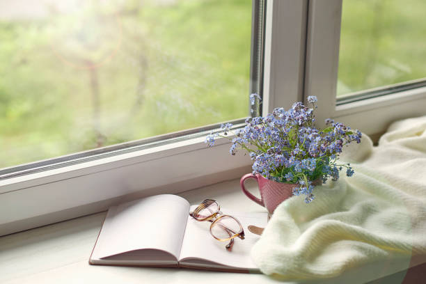 istock white warm plaid blanket and notebook, glasses on wooden rustic bench. Photo toned, selective focus. Cozy home still life: spring flowers with warm plaid on windowsill 1272732953