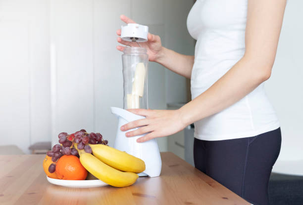 istock Young fit woman preparing a fruit smoothie for breakfast 1272733004