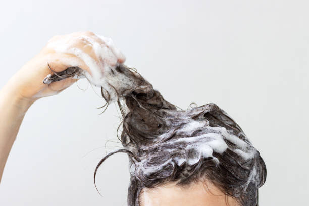 istock A girl washes her hair with shampoo on white background, front view 1272734050