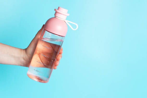 istock A woman's hand holds water bottle on blue background, copy space 1272734058