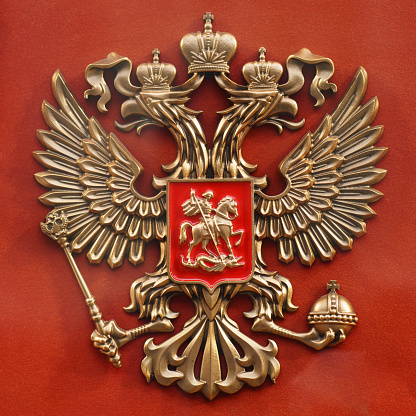 Moscow, Russia - September 10, 2020: Coat of arms of Russia. Two-headed eagle against red color background. Heraldry theme.\nCommemorative award. Family heirloom. The photo was taken in a home interior on a red background.
