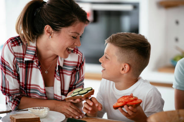 istock Mother and son eating sandwich in kitchen. 1272737146