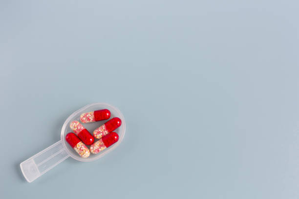 istock Multicolored pills or capsules on a measuring spoon on a blue background with copy space. 1272738348