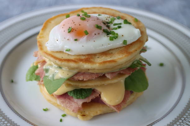 istock Image of stack of mini pancakes, florentine eggs benedict recipe, layers of pancake, bacon, spinach leaves, hollandaise sauce and poached egg, elevated view, focus on foreground 1272738545