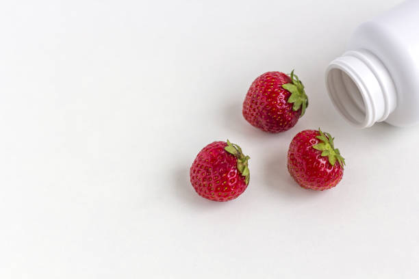 vitamine fresche come fragole dalla medicina bottiglia di pillola bianca su sfondo bianco. - alphabet letter n food fruit foto e immagini stock