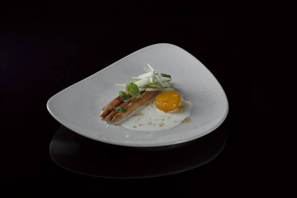 istock a vegetarian asparagus dish with green apple, cured egg yolk and basil on a cream colored ceramic plate on black reflective table 1272741444
