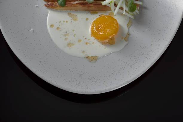 istock a vegetarian asparagus dish with green apple, cured egg yolk and basil on a cream colored ceramic plate shot from above on black reflective table 1272742055