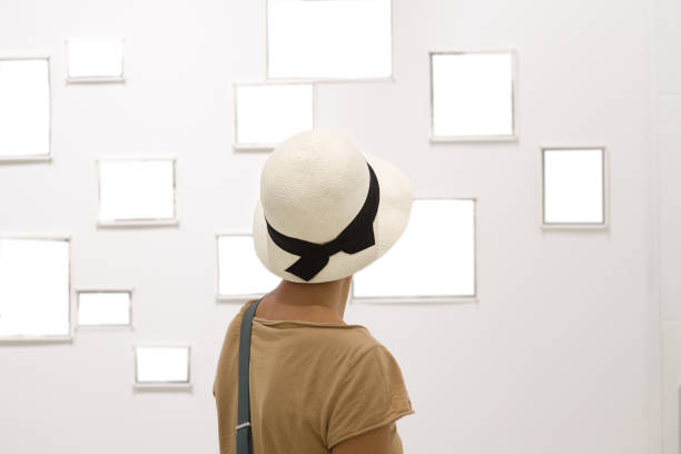istock a woman from back with a hat looks at empty picture frames hanging on the wall 1272743723