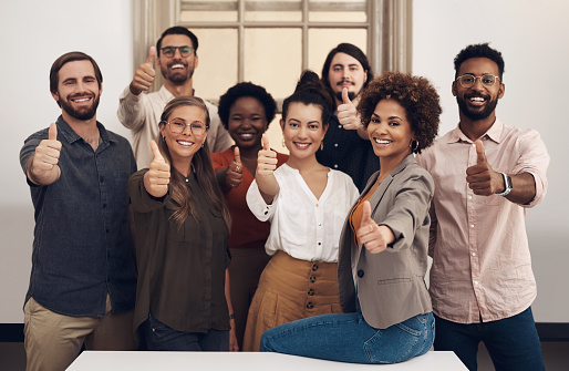 Portrait of a group of businesspeople showing thumbs up together in an office