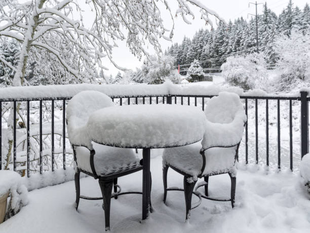 A snow covered deck, table and chairs. Overcast day causing a very monotone look. Small amount of colors showing.