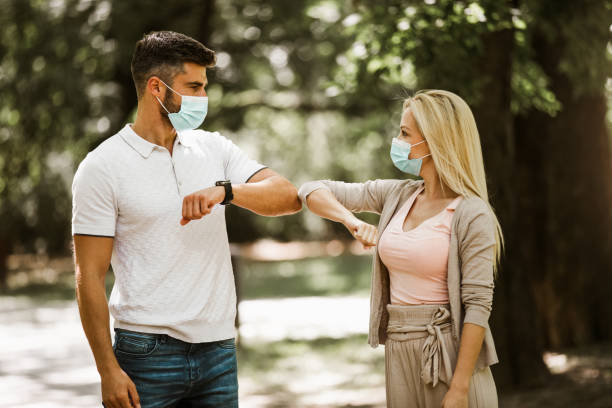istock Couple with masks bump elbows to avoid coronavirus outdoors 1272746965