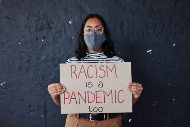Spread tolerance not sickness Studio shot of a masked young woman protesting against racism against a dark background police brutality photos stock pictures, royalty-free photos & images