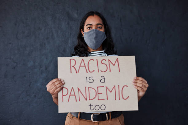 Discrimination is a real disease Studio shot of a masked young woman protesting against racism against a dark background police brutality photos stock pictures, royalty-free photos & images