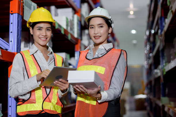 istock Engineer warehouse woman wearing a hardhat standing cargo at goods warehouse and check for control loading from Cargo freight ship for import and export by report on tablet. Teamwork concept 1272755323