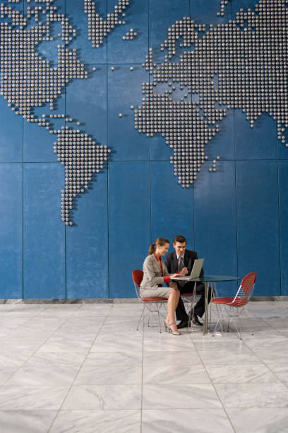 istock Business colleagues using laptop in office with world map on wall 1272756589