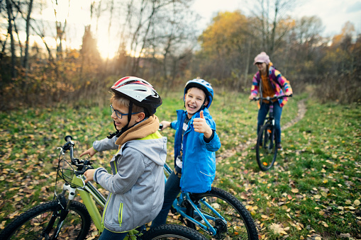Three kids riding bikes in autumn nature.\nNikon D850
