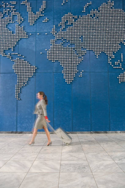 istock Business woman with suitcase walking past world map on wall 1272757202