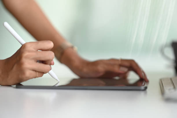 Closeup woman working on digital tablet using stylus pen on white table.