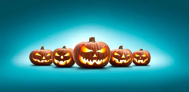 Five halloween, Jack O Lanterns, with evil spooky eyes and faces isolated against a blue lit background.