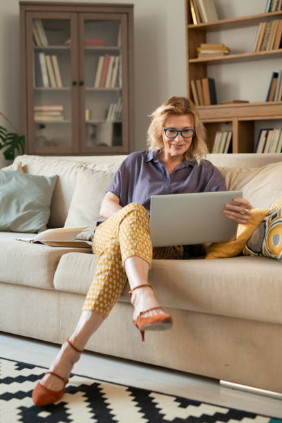 istock Mature blond businesswoman looking at tablet display while sitting on couch 1272761255