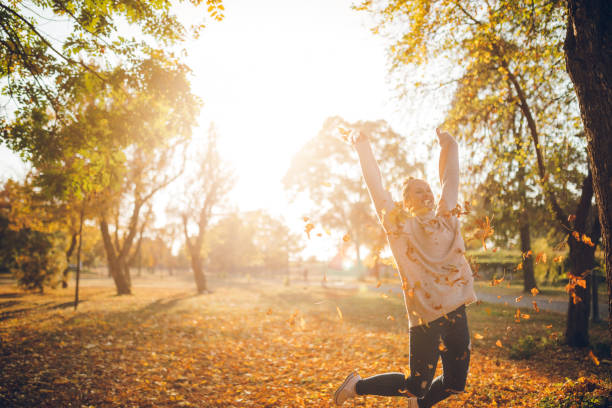 Teenage girl running and kicking leaves in autumn park.\n\nShot with Canon R5