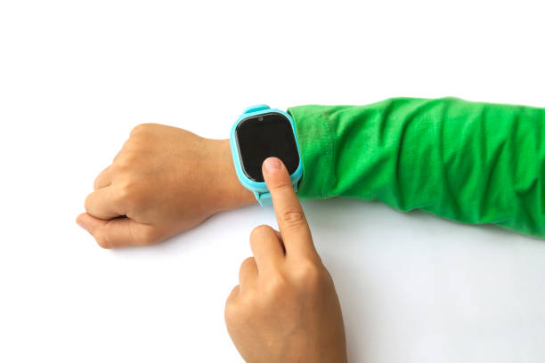 istock boy looks at information on digital clock pressing screen with his index finger. Modern childrens technologies. GPS tracker for kids, child tracking and parental control concept. 1272762377