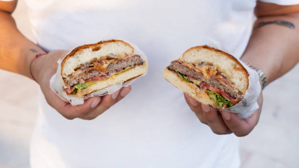 istock Burger cut in two parts held in hands 1272762581