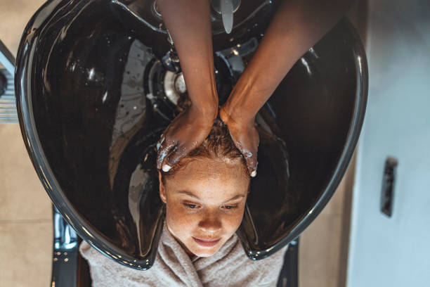Happy young woman at hair salon Woman applying shampoo and massaging hair of a customer. Woman having her hair washed in a hairdressing salon. black woman washing hair stock pictures, royalty-free photos & images