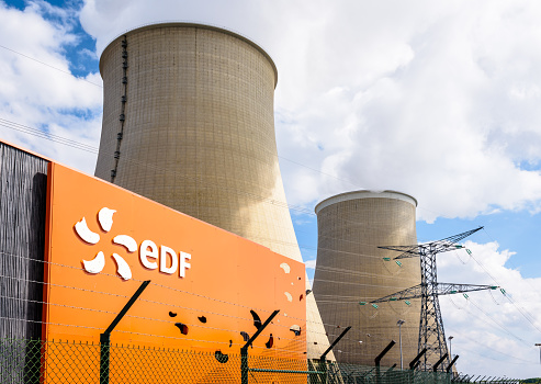 Nogent-sur-Seine, France - September 1, 2020: Low angle view of the EDF (Electricité de France) sign at the entrance of the nuclear power plant of Nogent-sur-Seine and the two cooling towers.
