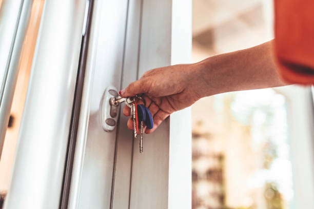 jeune femme ouvrant la porte d’entrée de son immeuble d’appartement - porte dentrée photos et images de collection