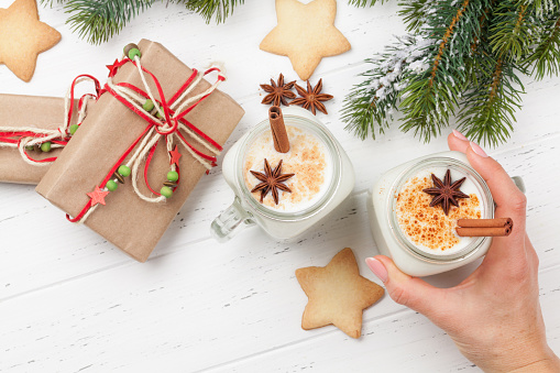 Eggnog. Traditional christmas cocktail and gingerbread cookies. With xmas gift boxes on wooden table. Flat lay. Top view with space for your greetings