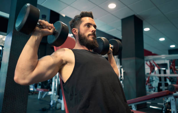 istock One young man lifting weights at the gym. 1272773133