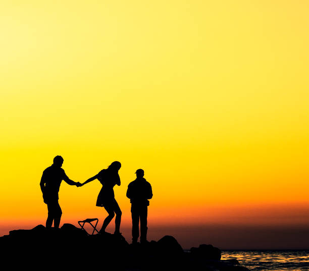 istock people at the sunset rocky shore 1272774595