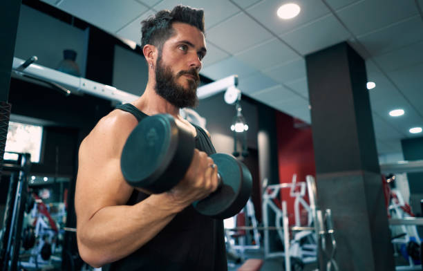 istock One young man lifting dumbbells at the gym. 1272774670