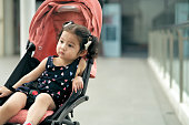 baby child sitting on Stroller outdoor waiting for her mother.