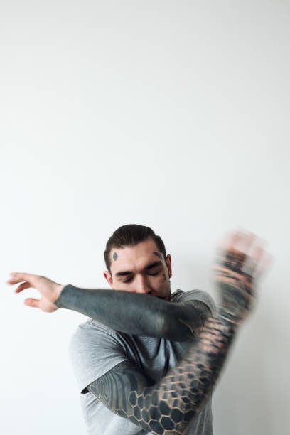 Tattooed man beating the air Tattooed man beating the air. Conceptual photo of young tattooed man swinging his arms aimlessly with his eyes closed against white wall background, blurred motion arm tattoo ideas for men pictures stock pictures, royalty-free photos & images