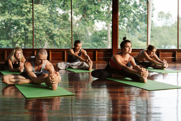 ludzie praktykujący jogę o poranku. - yoga class caucasian young adult group of people zdjęcia i obrazy z banku zdjęć