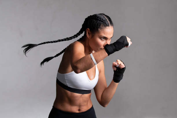 poinçonnage de boxeur de femme pendant l’entraînement - sport de combat photos et images de collection