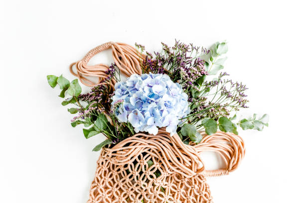 Beautiful bouquet of hydrangeas in a string, eco bag on white background. Flat lay, top view