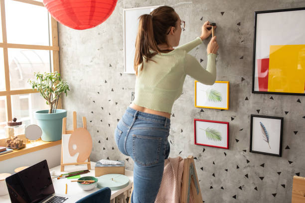 istock Young woman decorating living room 1272782908