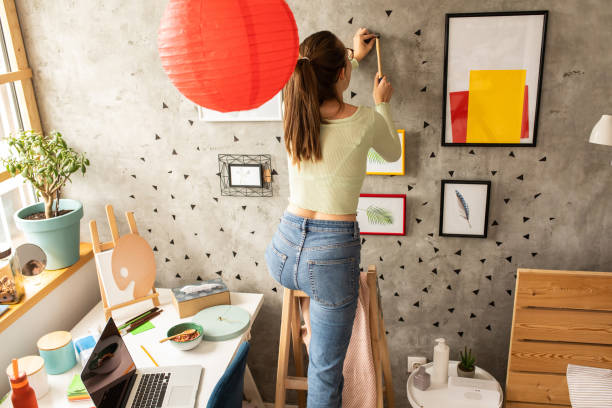 istock Young woman decorating living room 1272783069