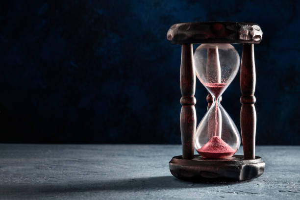 istock Time concept. An hourglass with sand falling through, on a dark background 1272785085