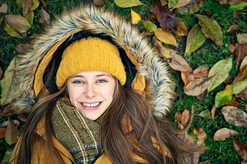 Autumn Portrait of a beautiful teenage girl lying on leaves.\nNikon D850
