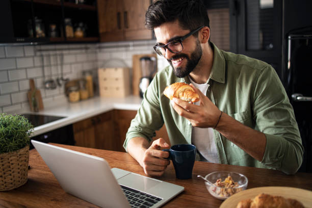 istock Happy man eating croissant in the kitchen 1272785976