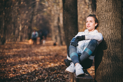 Young woman listening to music and resting after jogging